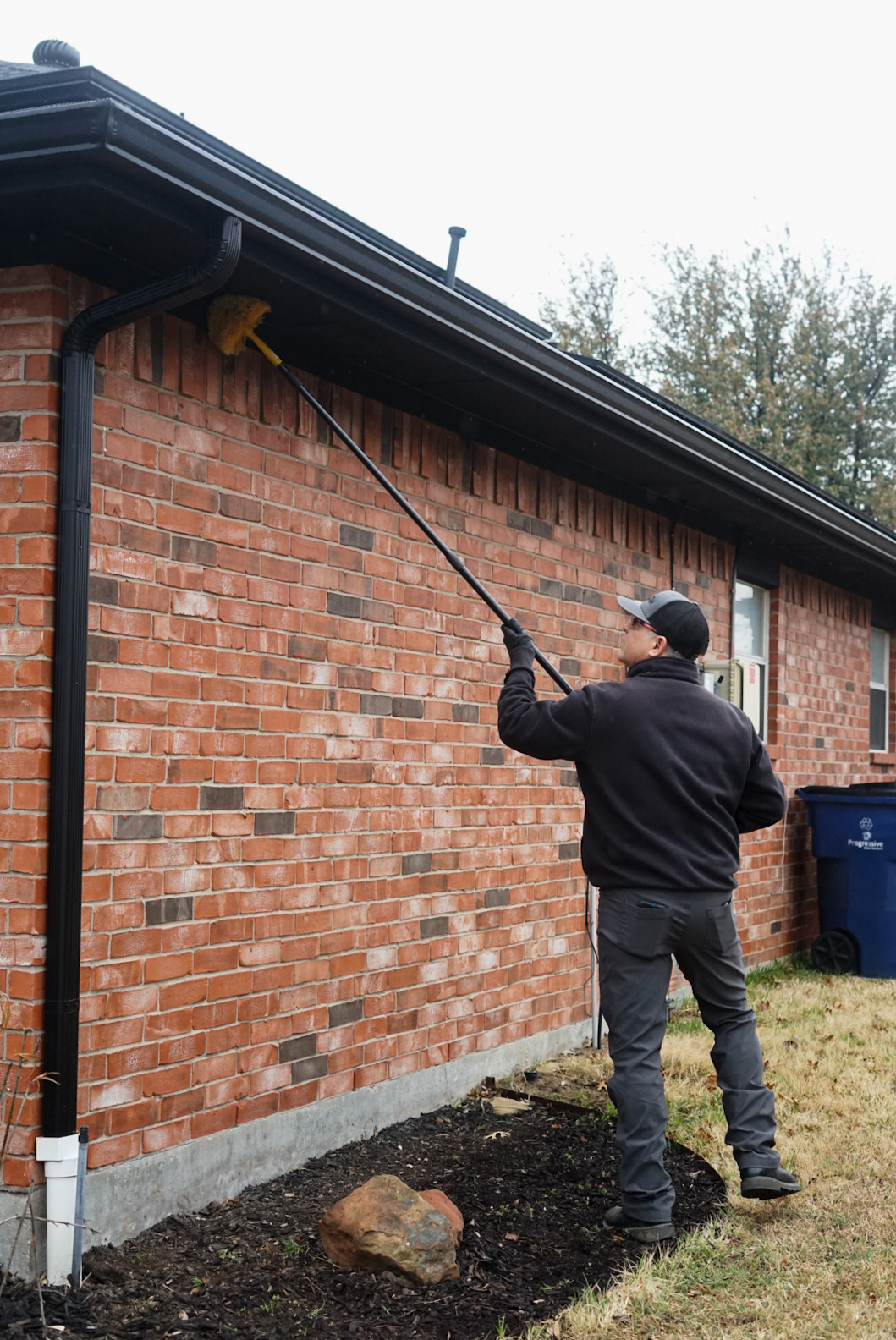 DANCAN Pest Control professional sweeping eaves of a home